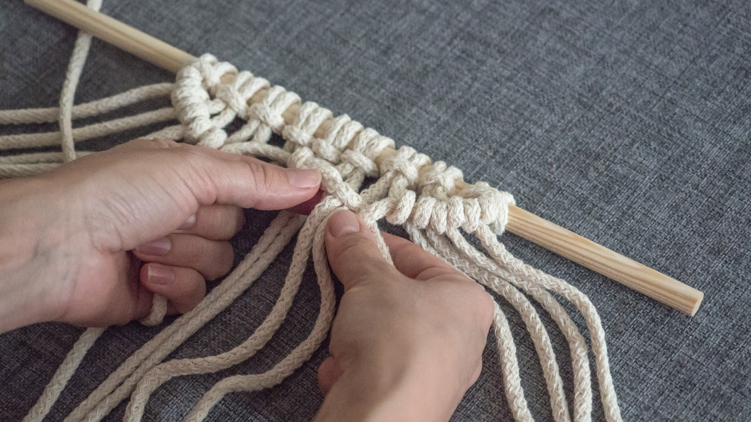 Macrame. Girl Weaves Macrame. White Thread, Female Hand, Grey Background, Close Up