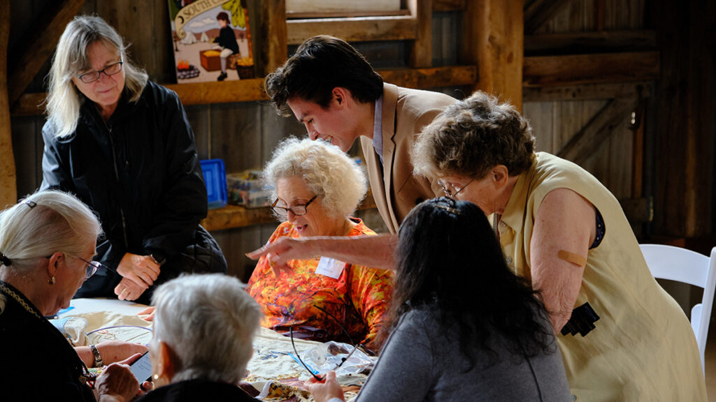 A group of women looking at a piece of embroidery together.